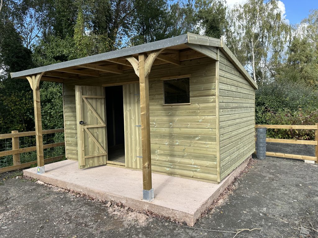 14x10 shed with a over hanging canopy of 4ft, apex roof with double doors with a window either side of the door