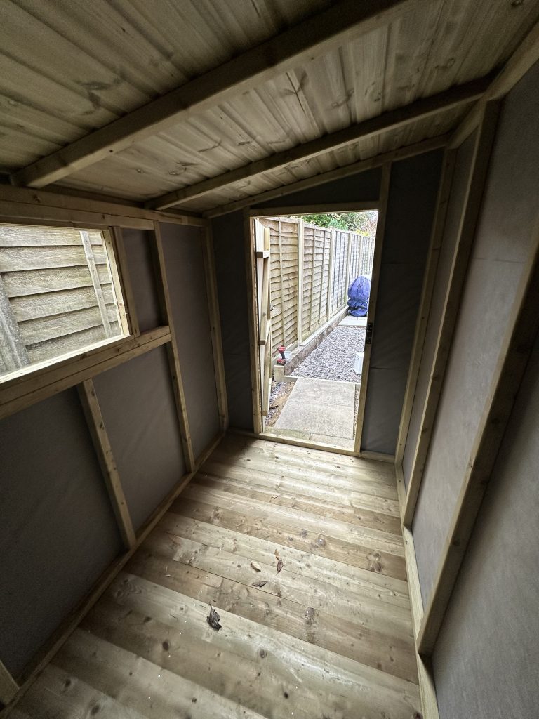 the inside of a 5x7 garden shed with a single window and single door.